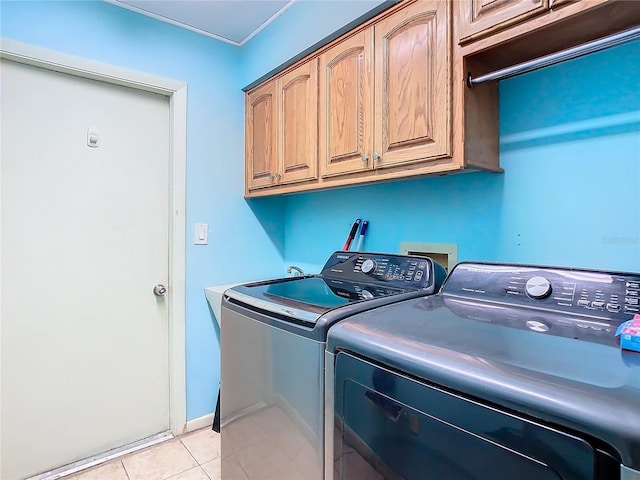 clothes washing area with light tile patterned floors, washing machine and dryer, and cabinets