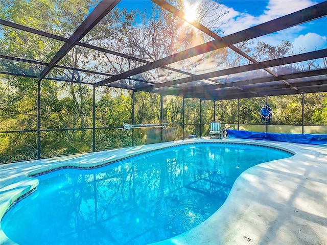 view of pool with glass enclosure and a patio