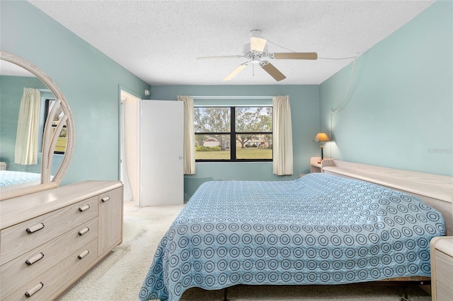 carpeted bedroom with ceiling fan and a textured ceiling