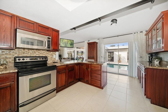 kitchen featuring appliances with stainless steel finishes, light stone counters, light tile patterned flooring, decorative backsplash, and kitchen peninsula