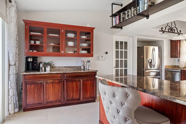 kitchen featuring stainless steel appliances, light tile patterned flooring, lofted ceiling, and light stone counters