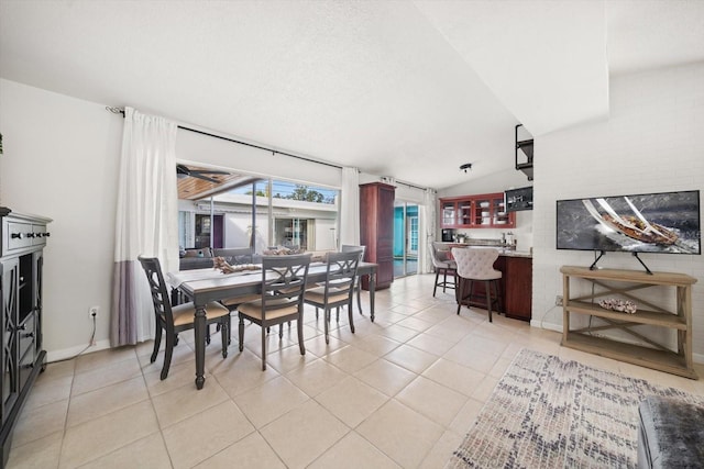 tiled dining space featuring lofted ceiling and indoor bar