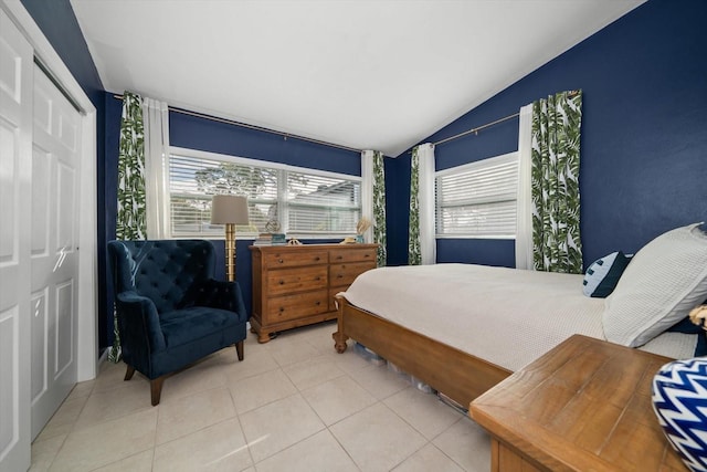 bedroom with lofted ceiling, light tile patterned floors, and a closet