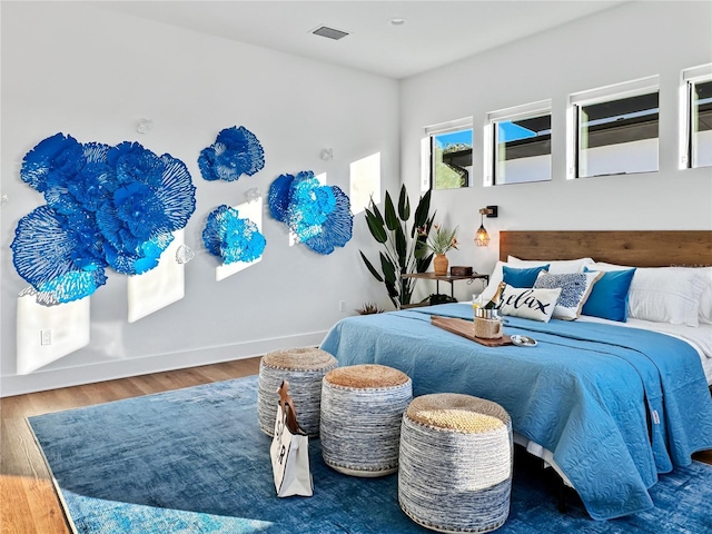 bedroom featuring visible vents, baseboards, and wood finished floors