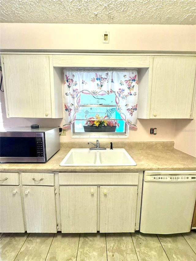 kitchen featuring sink, a textured ceiling, light tile patterned floors, and dishwasher