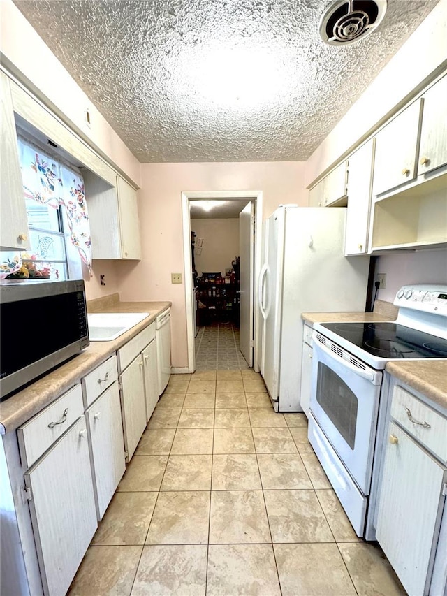 kitchen with light tile patterned floors, white appliances, white cabinetry, and a textured ceiling