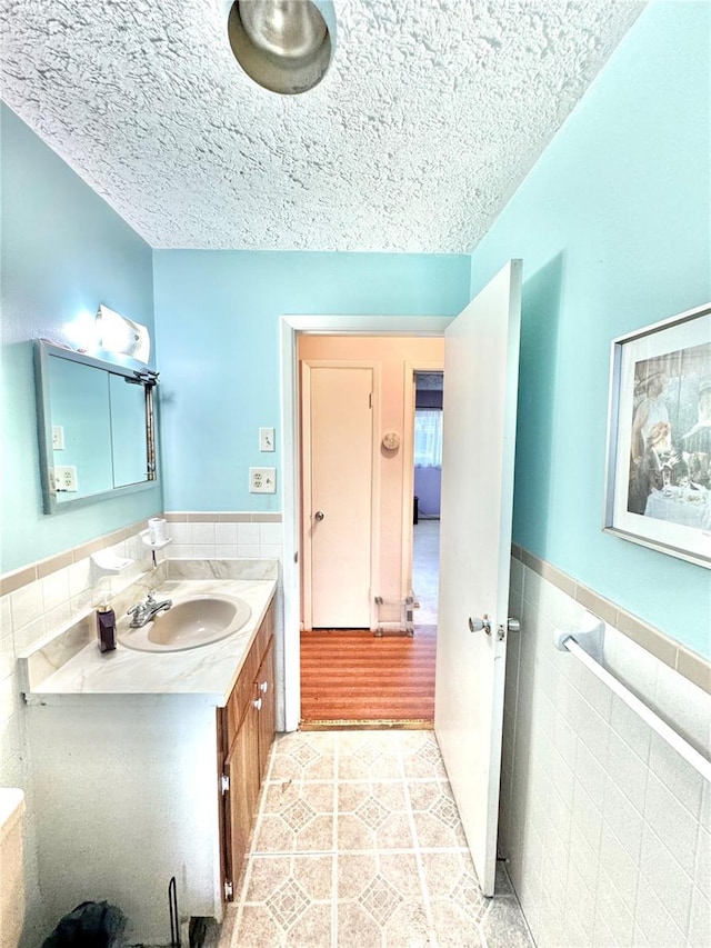 bathroom with vanity, tile walls, tile patterned floors, and a textured ceiling