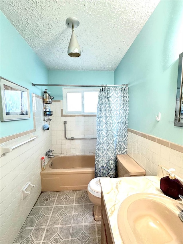 full bathroom with a textured ceiling, toilet, vanity, and shower / tub combo with curtain