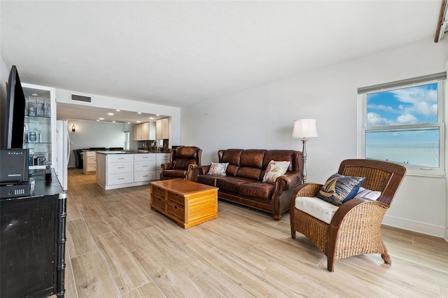 living room with light wood finished floors, visible vents, and baseboards