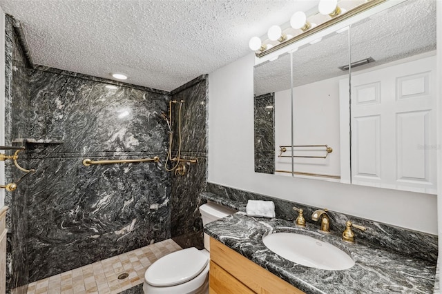 full bath with a textured ceiling, vanity, a marble finish shower, and toilet