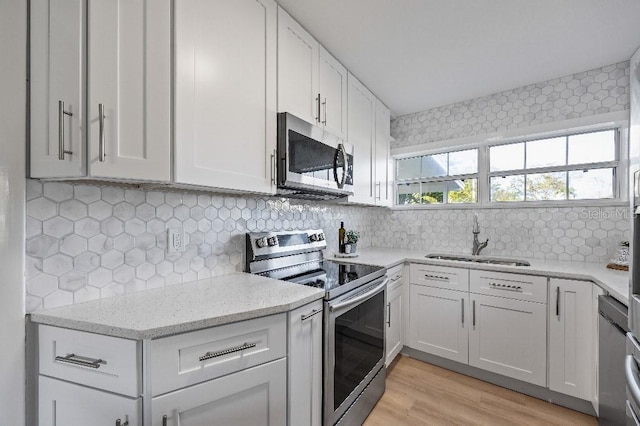 kitchen with appliances with stainless steel finishes, backsplash, white cabinetry, and sink