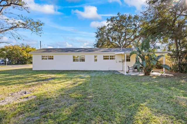 back of property with a lawn and a patio