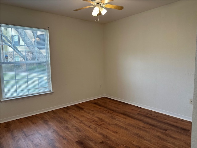 spare room featuring a healthy amount of sunlight, dark hardwood / wood-style flooring, and ceiling fan