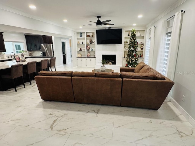 living room with sink, built in features, ceiling fan, and a fireplace