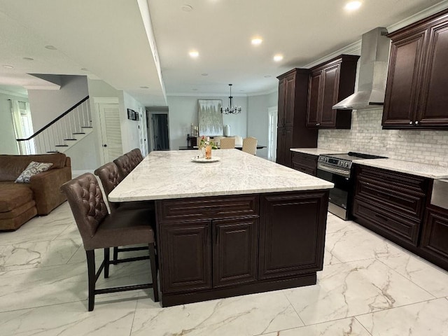 kitchen with stainless steel range with electric stovetop, a center island, wall chimney exhaust hood, and a kitchen bar