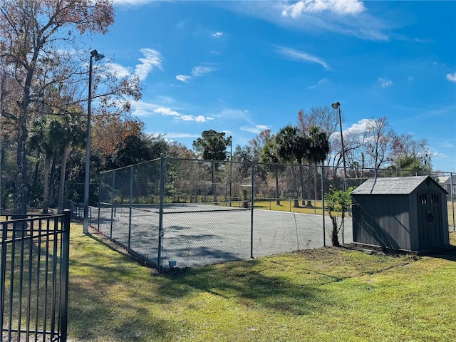 view of tennis court featuring a storage shed and a yard