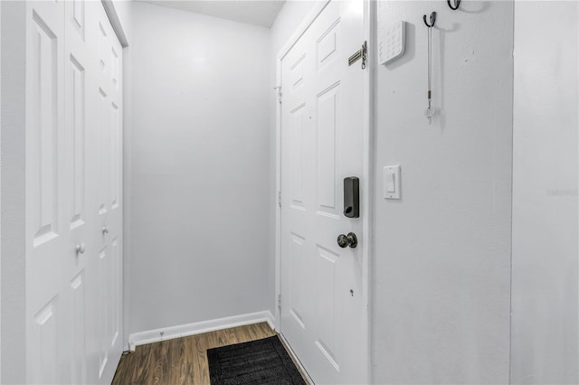 doorway featuring baseboards and dark wood finished floors