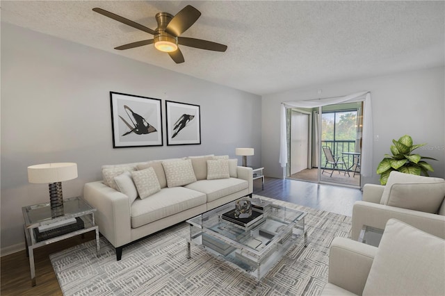 living area featuring a ceiling fan, a textured ceiling, baseboards, and wood finished floors