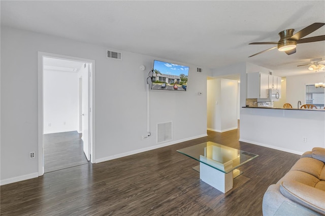 unfurnished living room with baseboards, visible vents, and dark wood-style flooring