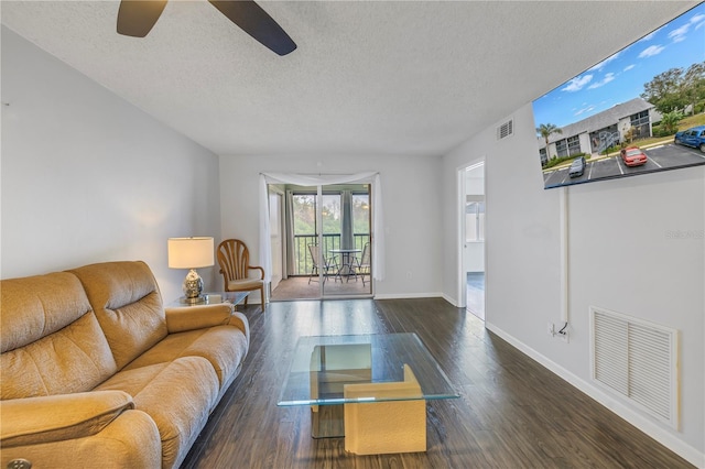 living room featuring a textured ceiling, wood finished floors, visible vents, and baseboards