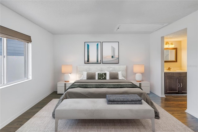 bedroom featuring attic access, baseboards, dark wood finished floors, and a textured ceiling