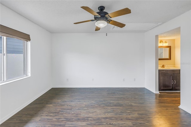 empty room with ceiling fan, baseboards, dark wood finished floors, and a textured ceiling