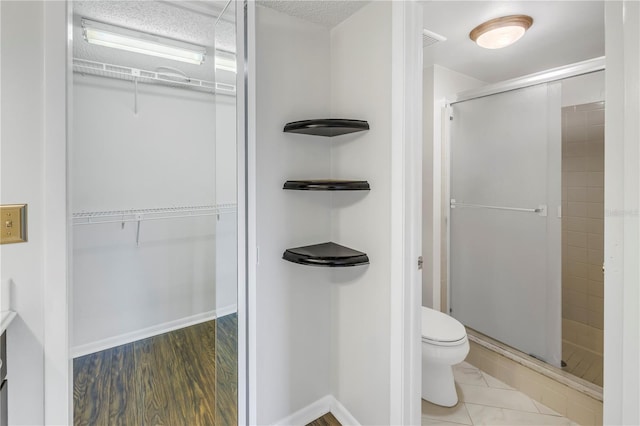 full bath featuring a spacious closet, a stall shower, toilet, and baseboards