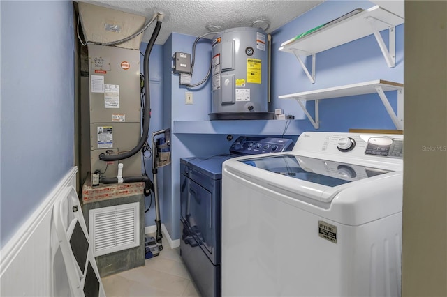 washroom featuring light tile patterned floors, electric water heater, a textured ceiling, laundry area, and independent washer and dryer