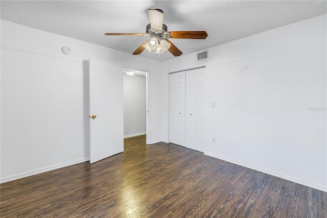 unfurnished bedroom with a textured ceiling, wood finished floors, visible vents, baseboards, and a closet