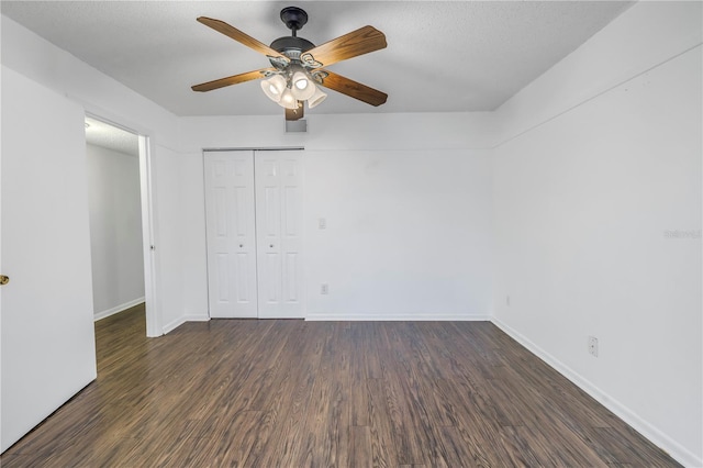 unfurnished bedroom with a textured ceiling, a closet, baseboards, and wood finished floors