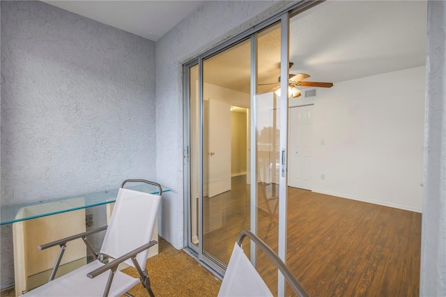 home office featuring ceiling fan, wood finished floors, and a textured wall