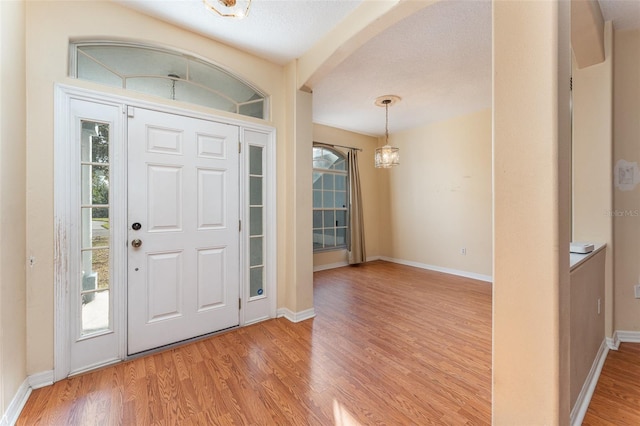 foyer entrance featuring a textured ceiling, light hardwood / wood-style floors, and a chandelier