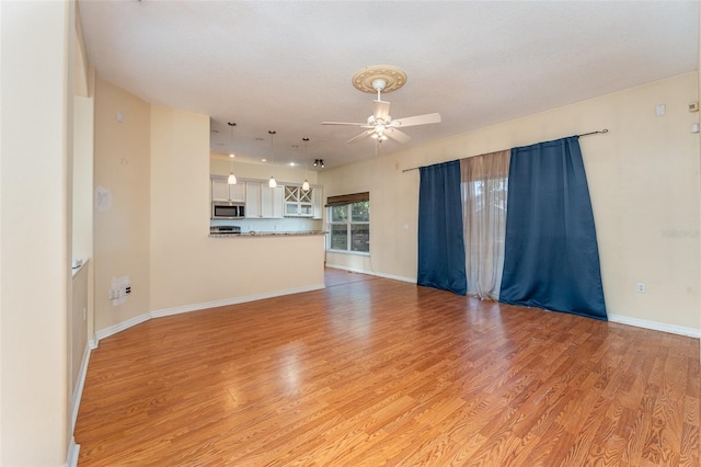 unfurnished living room featuring ceiling fan and light hardwood / wood-style flooring