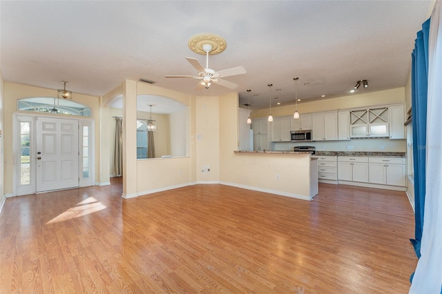 kitchen featuring stainless steel appliances, white cabinetry, kitchen peninsula, and pendant lighting