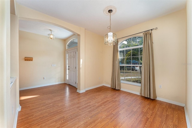 spare room featuring an inviting chandelier and light hardwood / wood-style floors