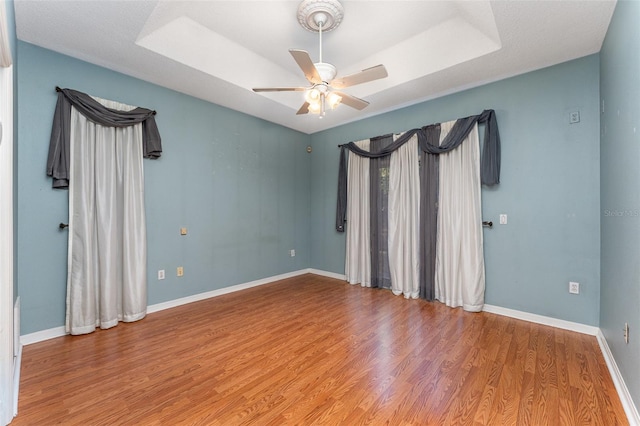 empty room featuring ceiling fan, a tray ceiling, and hardwood / wood-style floors