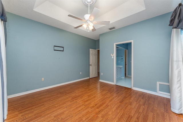 unfurnished bedroom featuring a textured ceiling, ceiling fan, light hardwood / wood-style flooring, and connected bathroom