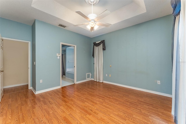 unfurnished bedroom featuring a textured ceiling, ceiling fan, light hardwood / wood-style flooring, and connected bathroom