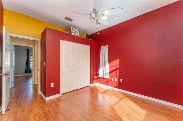 unfurnished bedroom with ceiling fan, a closet, and hardwood / wood-style floors