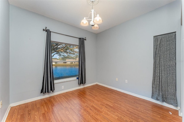 unfurnished room featuring wood-type flooring and a chandelier