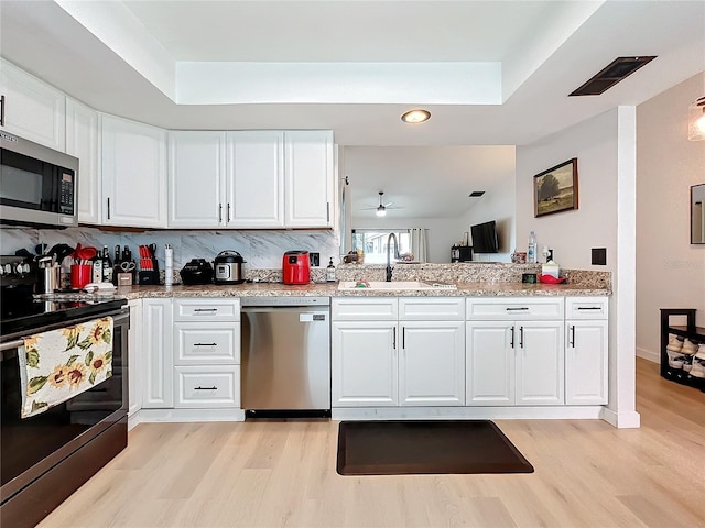 kitchen featuring appliances with stainless steel finishes, white cabinetry, backsplash, and sink