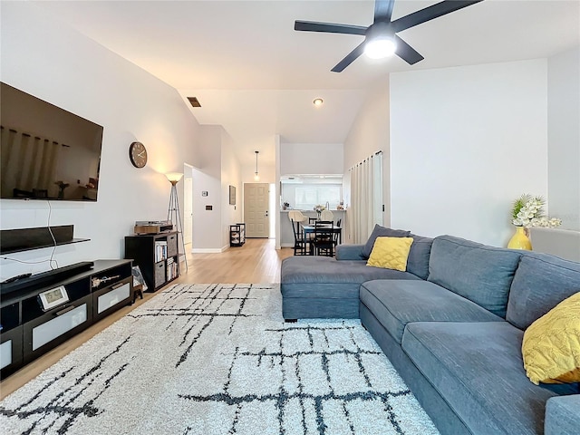 living room with ceiling fan, vaulted ceiling, and light hardwood / wood-style flooring