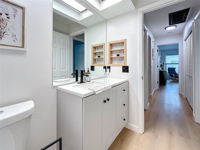 bathroom with toilet, vanity, and hardwood / wood-style flooring