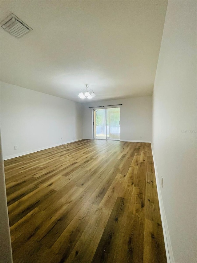 empty room featuring hardwood / wood-style flooring and an inviting chandelier