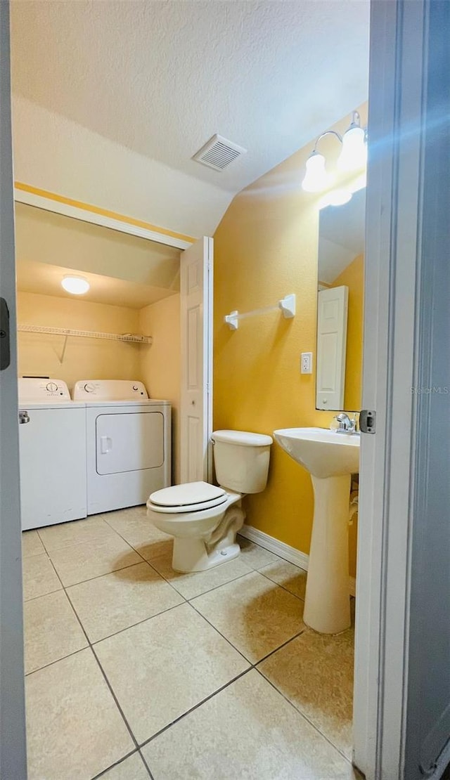 bathroom featuring separate washer and dryer, tile patterned flooring, toilet, a textured ceiling, and sink