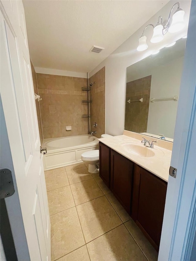 full bathroom with tiled shower / bath, tile patterned flooring, vanity, and toilet