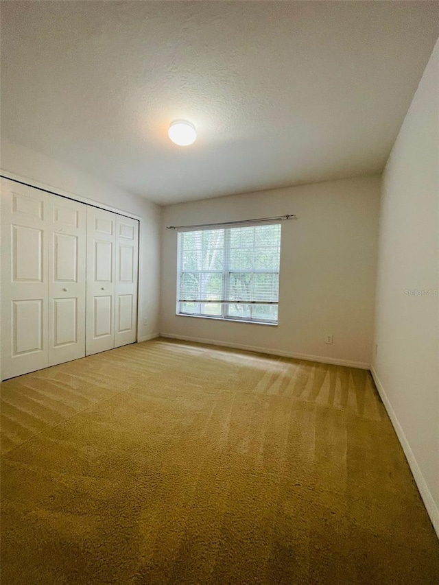 unfurnished bedroom with a textured ceiling, carpet floors, and a closet