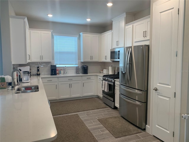 kitchen featuring stainless steel appliances, backsplash, white cabinets, and sink