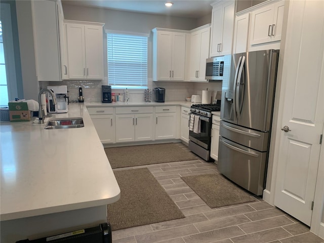 kitchen with appliances with stainless steel finishes, white cabinets, tasteful backsplash, and sink