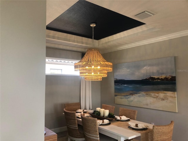 dining area with a notable chandelier, a tray ceiling, and ornamental molding